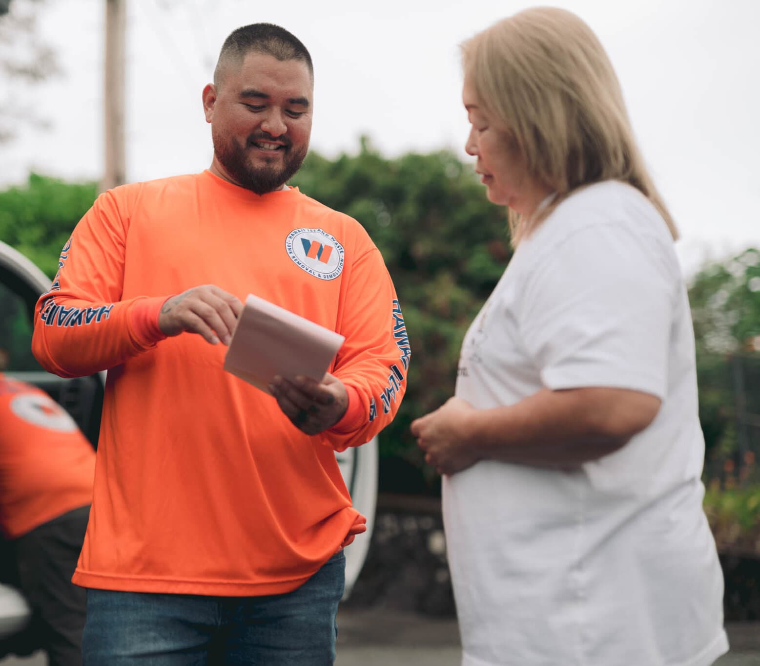 Naea Kaopua, owner of Hawaii Island Waste, reviewing a job estimate with a customer